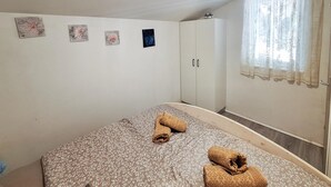 Ett sovrum med en säng, en garderob och ett fönster med gardiner.