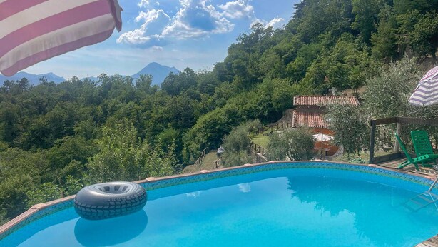 Ein Schwimmbecken mit freiem Blick auf eine gebirgige Landschaft im Hintergrund.