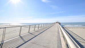 Eine Pier, die sich ins Meer erstreckt, mit blauem Himmel darüber.