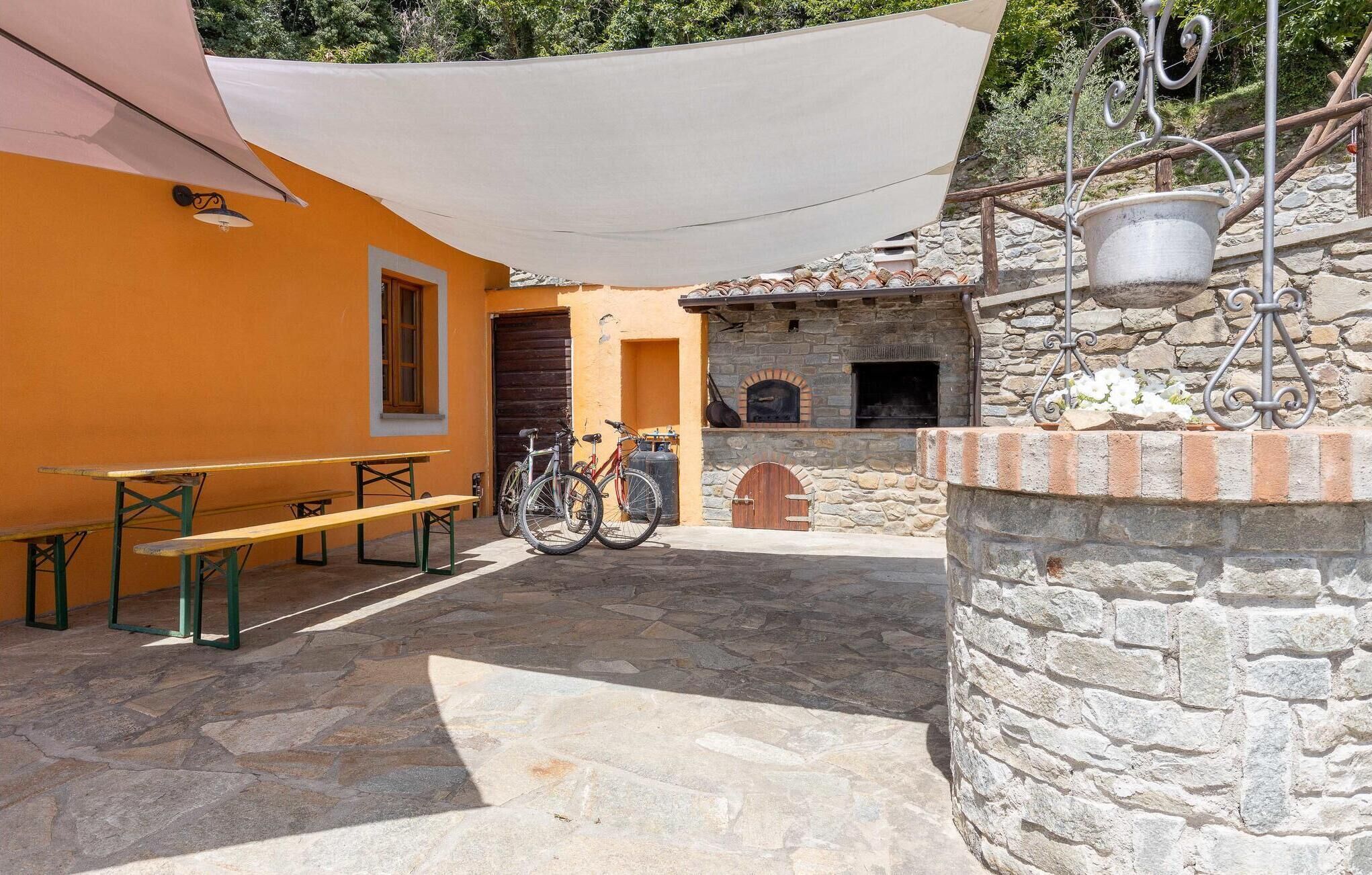A courtyard with stone flooring, outdoor seating, a bicycle, and a stone oven.