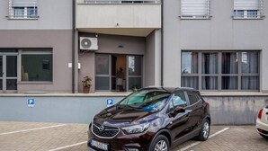 Ein mehrstöckiges Wohngebäude mit einem parkenden Auto davor.