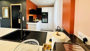 Une cuisine moderne avec des armoires blanches, un robinet noir et un four encastré.