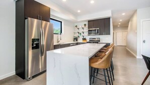 A modern kitchen with a large island, stainless steel appliances, and a minimalist design. - 90 min from Chicago, Pool, Hot Tub, Pet Friendly come enjoy After Dune Delight (Stevensville)