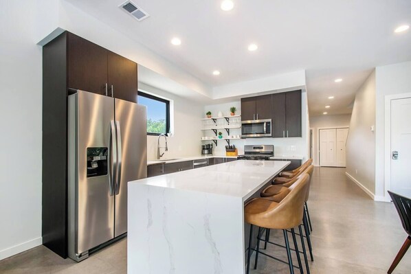 A modern kitchen with a large island, stainless steel appliances, and a minimalist design.