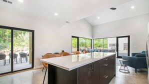 A modern kitchen with a large island, dining area with chairs, and a sofa. - 90 min from Chicago, Pool, Hot Tub, Pet Friendly come enjoy After Dune Delight (Stevensville)