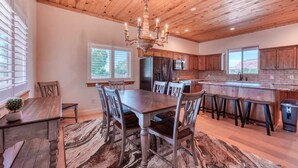 Une cuisine spacieuse avec des meubles en bois, un coin repas doté d’une grande table et de chaises, et un lustre.