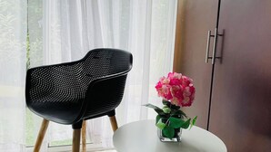 A room with a black perforated chair, a small white table with a potted plant, and a dark wooden cabinet. - Hotel Rosalinda Campestre del Llano (Villavicencio)