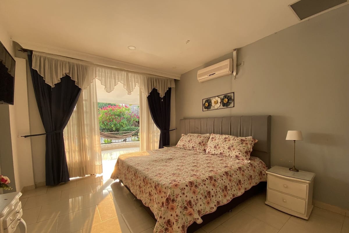A bedroom with a bed, nightstand, and an air conditioning unit.