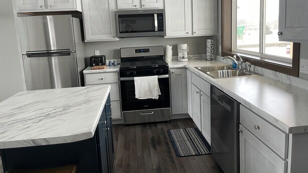 A modern kitchen with white cabinets, stainless steel appliances, and a marble countertop.