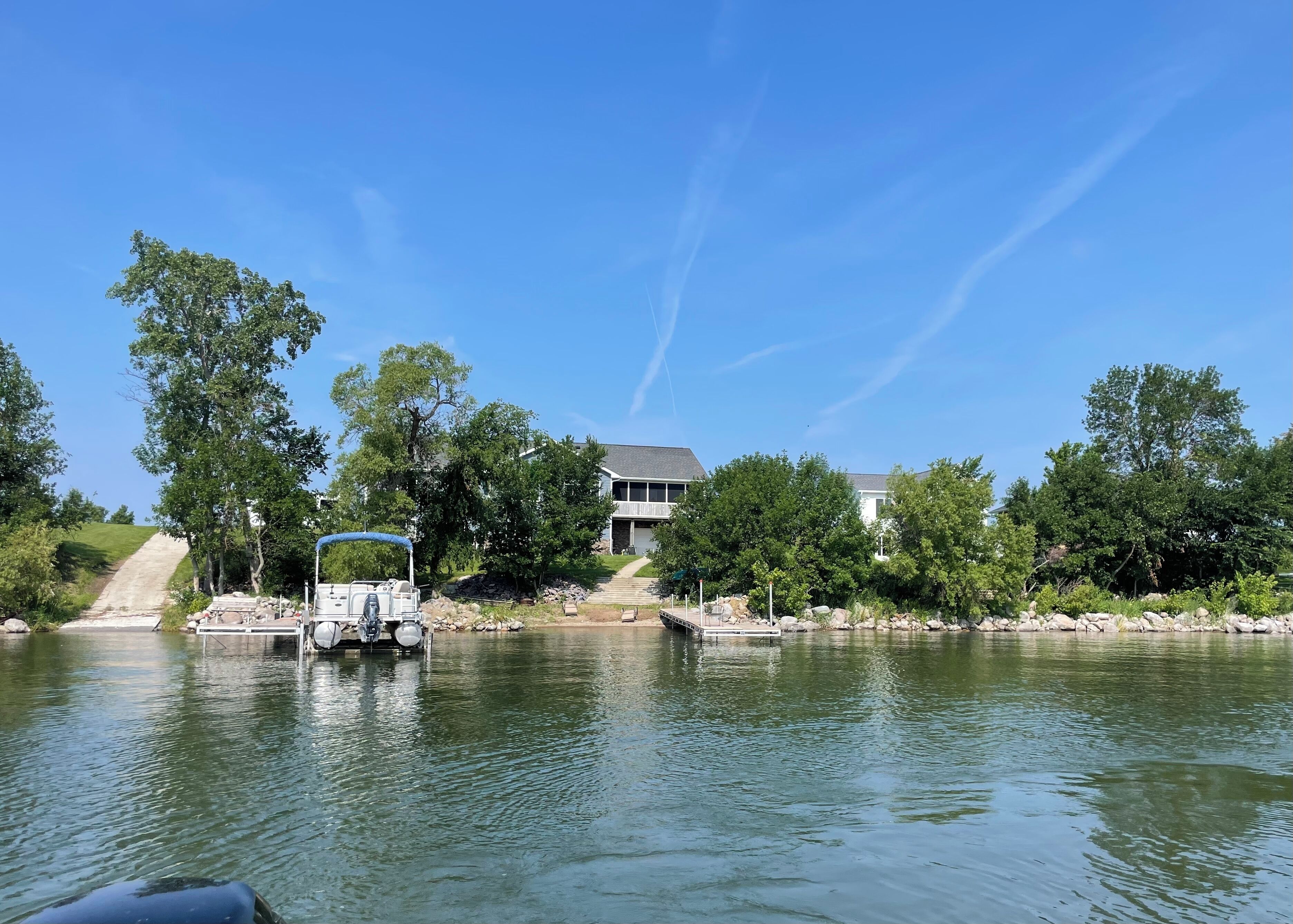Une maison au bord d’un lac, avec un quai et un bateau.