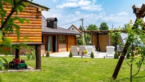 Una cabaña de troncos con porche cubierto, mobiliario exterior y jardín.