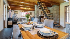 Un comedor con una mesa de madera dispuesta para una comida, una pared de piedra y una escalera de madera.