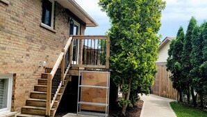 A brick house with a wooden staircase leading to a deck. - Niagara Luxury villa-Breakfast, pool, water view (Niagara Falls)