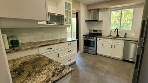 A modern kitchen with white cabinets, granite countertops, a built-in microwave, a stove, and a dishwasher. - Niagara Luxury villa-Breakfast, pool, water view (Niagara Falls)