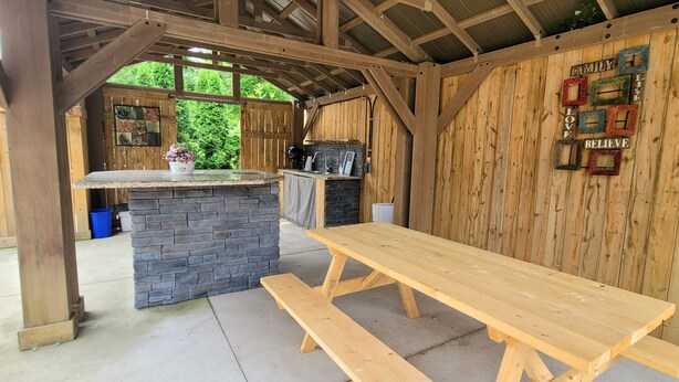 A rustic wooden structure with a stone counter and a wooden bench. - Niagara Luxury villa-Breakfast, pool, water view (Niagara Falls)