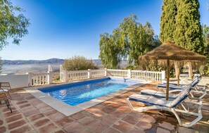 A swimming pool with a white fence, lounge chairs, and a thatched umbrella. - Beautiful home in Periana (Periana)