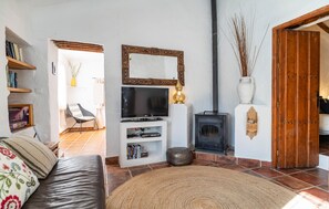 A cozy living room with a TV, bookshelf, fireplace, and a sofa. - Beautiful home in Periana (Periana)