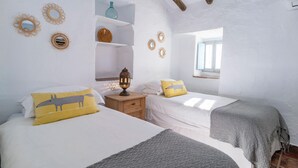 A bedroom with two beds, a nightstand, a shelf with decorative items, and a window. - Beautiful home in Periana (Periana)