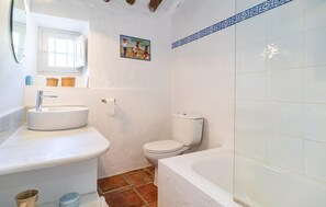 A bathroom with a white sink, toilet, and bathtub. There is a window above the sink and a painting on the wall. - Beautiful home in Periana (Periana)