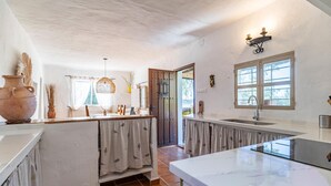 A kitchen with white walls, a large window, and a rustic wooden door. - Beautiful home in Periana (Periana)