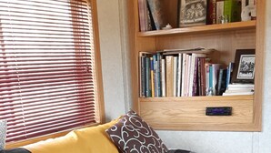 Un espacio de sala acogedor con un sofá seccional gris oscuro, una estantería de madera y una pequeña mesa.