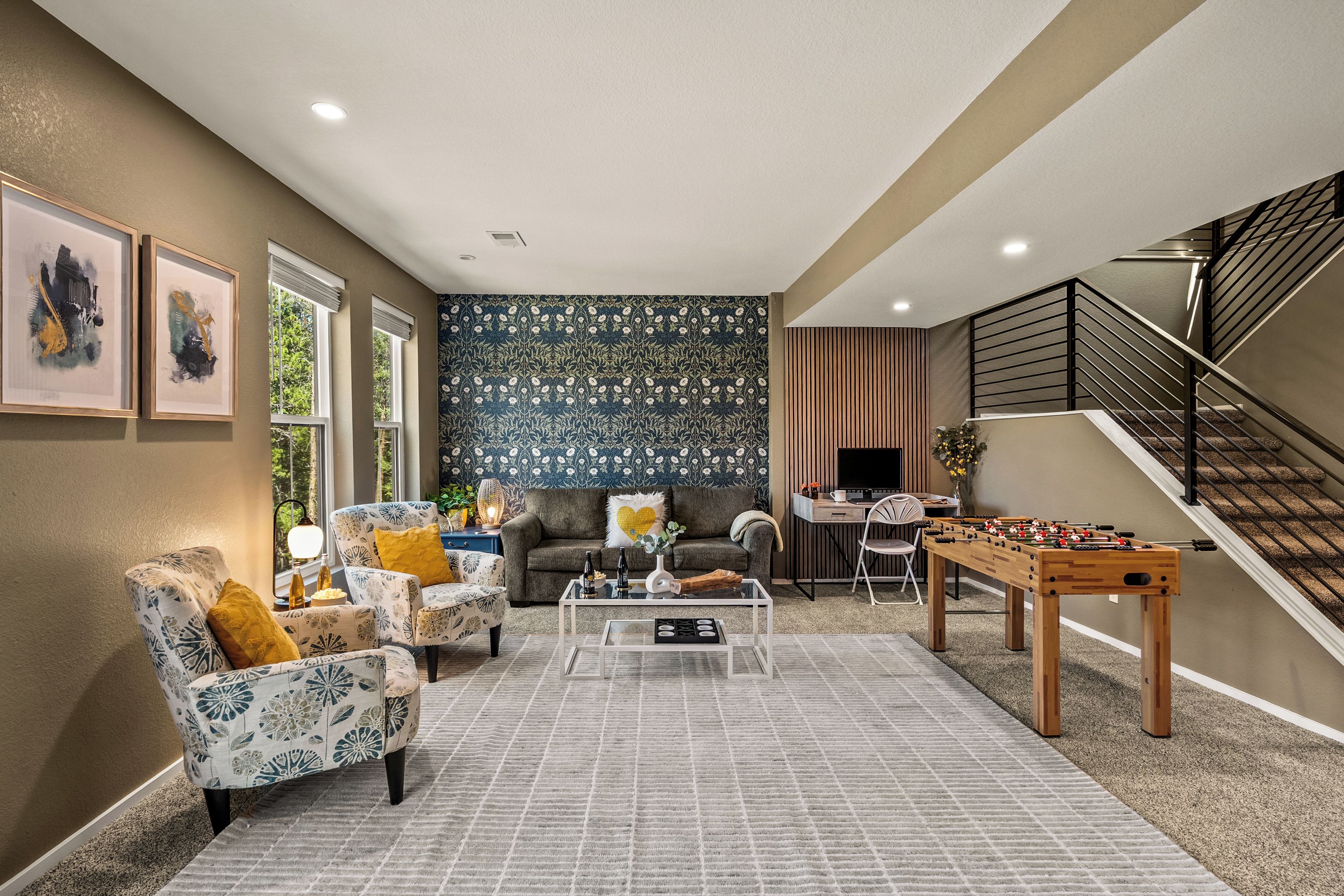 Uma sala de estar moderna com sofá, poltronas, mesa de centro e mesa de futebol.