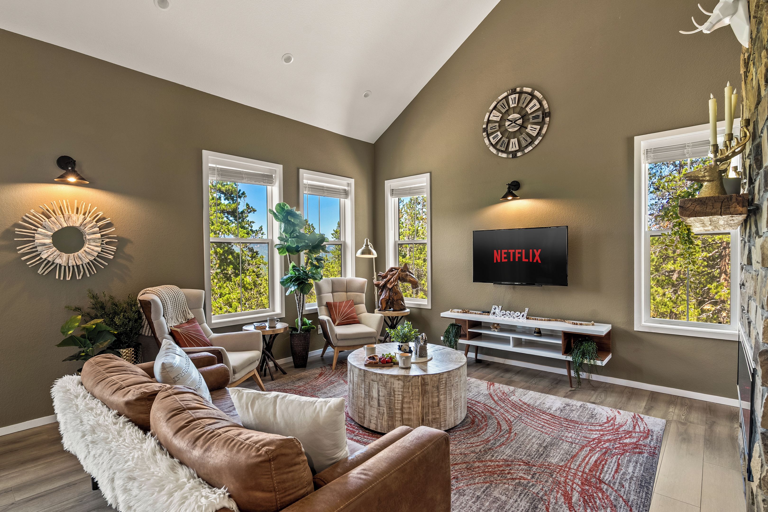 Uma sala de estar moderna com um sofá marrom, uma mesa de centro e uma TV fixada na parede.
