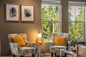 A room with two patterned armchairs, a small table with a lamp, and framed artwork on the wall. - LUXE MTN Retreat, EPIC views, Hot tub, STARGAZING Bed, Firepit, Red Rocks (Bailey)