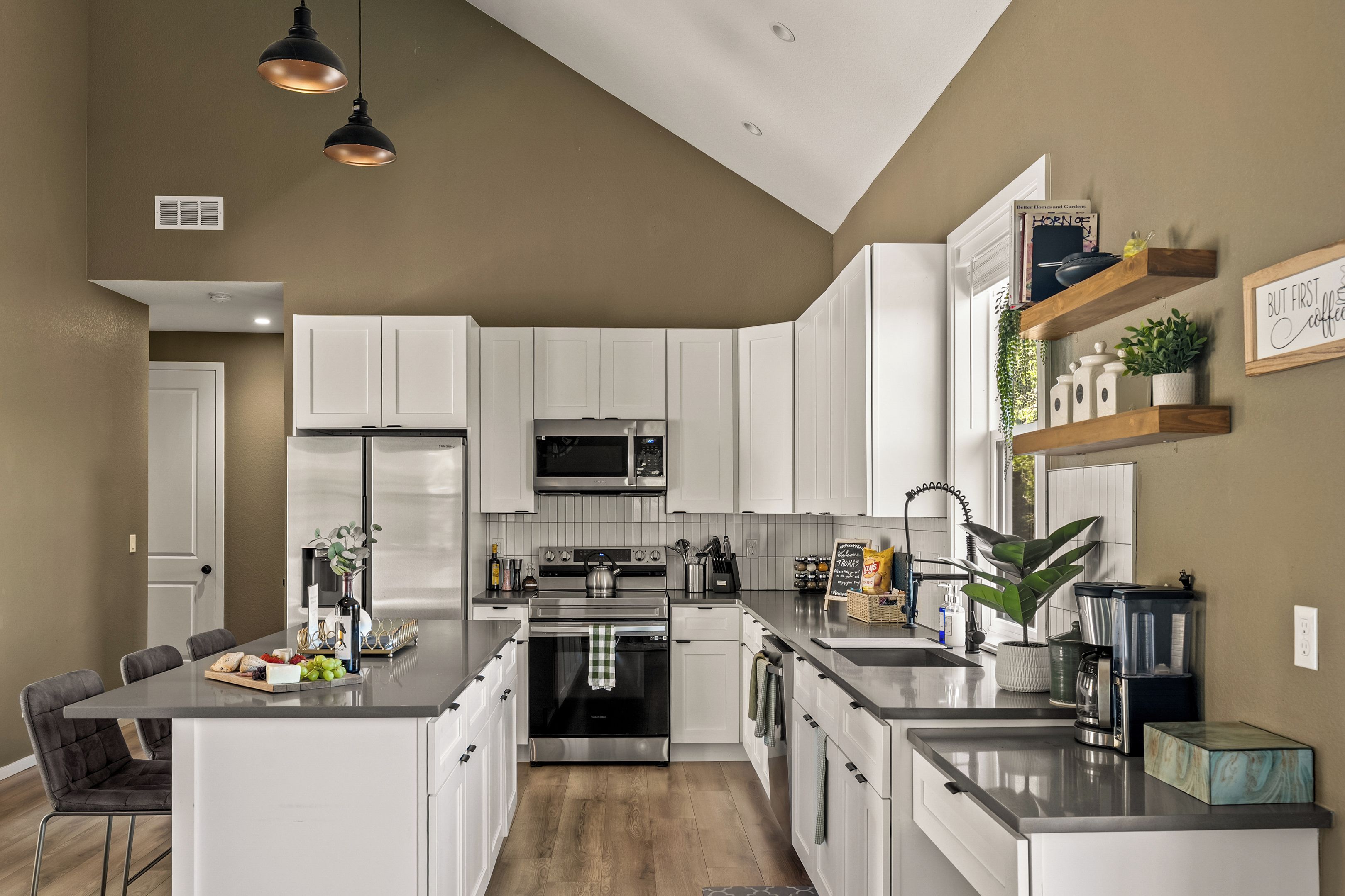 A modern kitchen with white cabinetry, stainless steel appliances, and a central island.