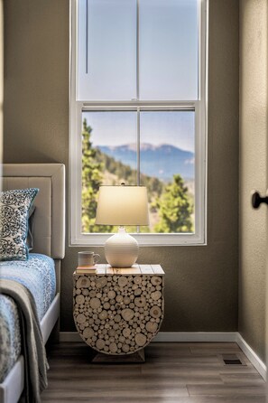 A bedroom with a bed, a bedside table with a lamp, and a view of mountains through a window. - LUXE MTN Retreat, EPIC views, Hot tub, STARGAZING Bed, Firepit, Red Rocks (Bailey)