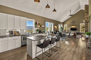 A spacious kitchen with a large island, bar stools, and a dining area with a high ceiling and stone accents. - LUXE MTN Retreat, EPIC views, Hot tub, STARGAZING Bed, Firepit, Red Rocks (Bailey)