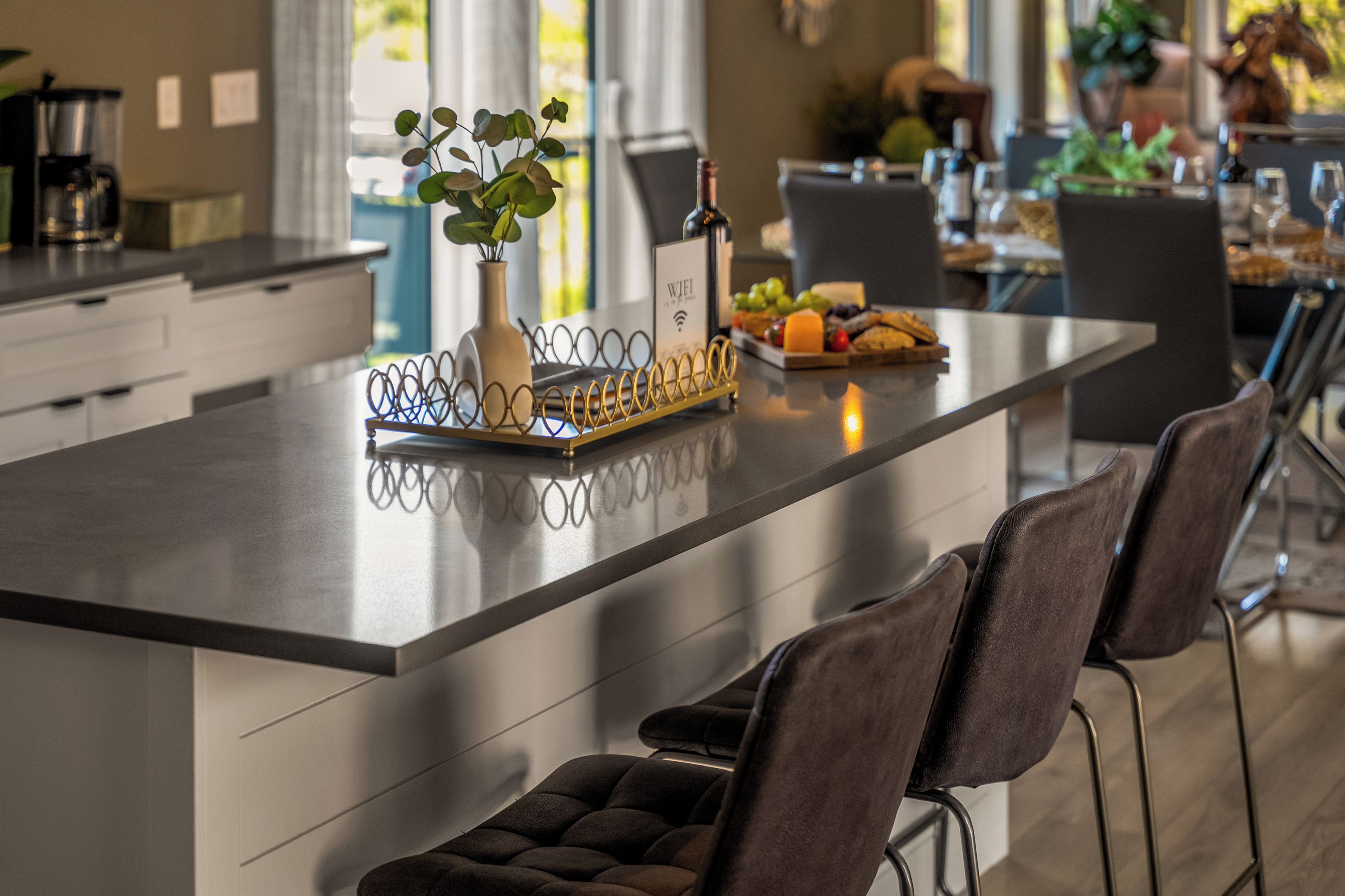 Cozinha moderna com ilha central, banquetas de bar e área de jantar com mesa posta para refeição.