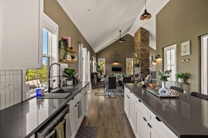 A modern kitchen with a central island, a dining area, and a stone fireplace. - LUXE MTN Retreat, EPIC views, Hot tub, STARGAZING Bed, Firepit, Red Rocks (Bailey)