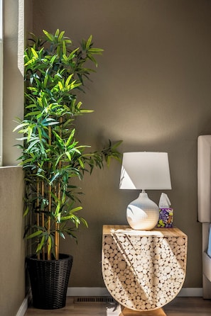 Rincón con una planta de bambú en maceta, una lámpara sobre una mesita de madera y una pared con textura.