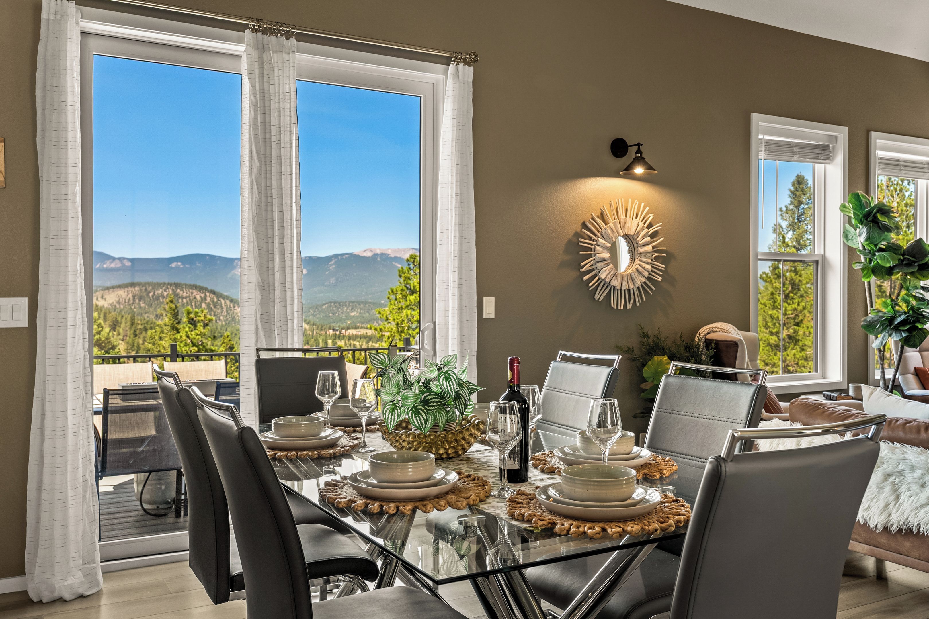 Comedor con mesa dispuesta para seis personas, con vista a un paisaje montañoso.