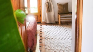 Una camera accogliente con un letto di legno, un tappeto trapuntato e una finestra con tende.