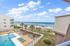 A pool area with lounge chairs and a view of the beach.