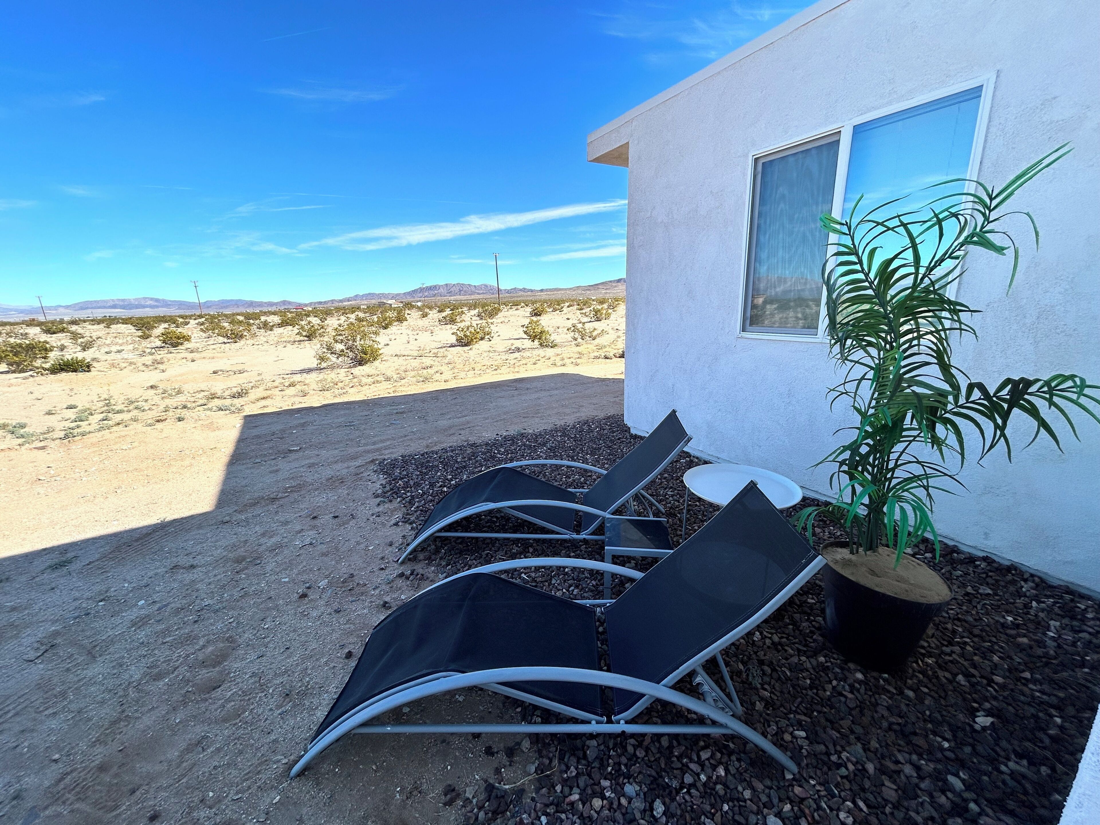 Un paysage désertique avec un bâtiment doté d’une fenêtre et d’une plante en pot.