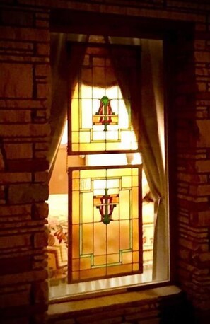 A stained glass window with a geometric design, set in a brick wall. - The Idyll: Stay in a re-purposed church (Winslow)