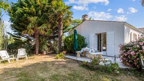 A house with a garden, a table with chairs, and a large tree.