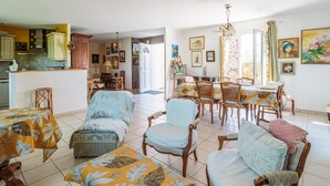 A spacious living room with a dining area, featuring a large table and multiple chairs.