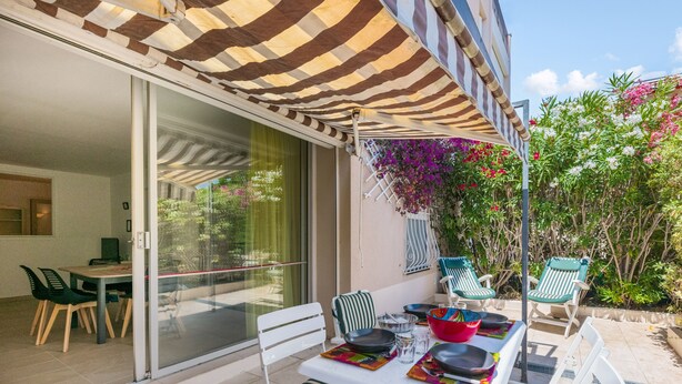 A patio with a table set for dining, outdoor chairs, and a striped awning.