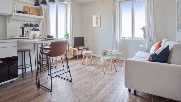 Et moderne opholdsrum med et køkken, spiseplads og siddeområde.