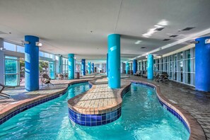 Ein Innenpool mit blau gefliesten Rändern, umgeben von blauen Säulen und Liegestühlen.