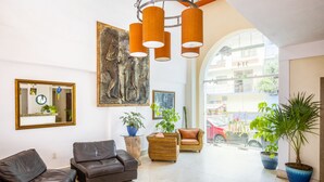 A spacious lobby with a high ceiling, modern furniture, and large windows offering a view of the street. - HOTEL PUEBLITO VALLARTA (Puerto Vallarta)