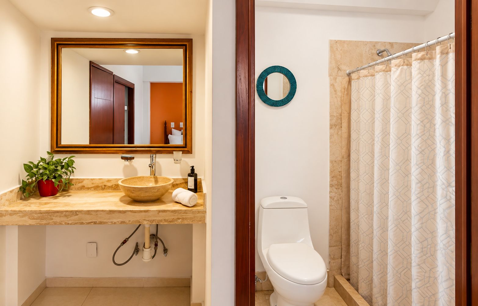 Une salle de bain équipée d’un lavabo, d’un miroir, de toilettes et d’un rideau de douche.