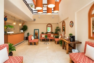 A hotel lobby with a reception desk, seating area with patterned sofas, and a coffee station.
