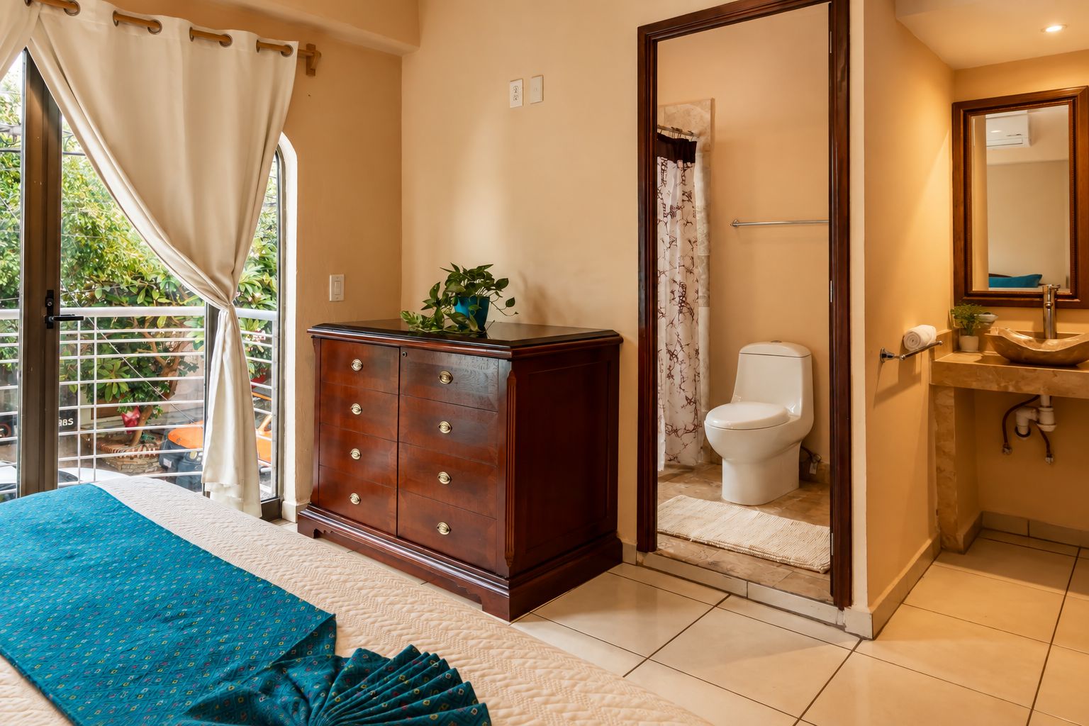 Un dormitorio con cama, cómoda, baño con inodoro y ducha.