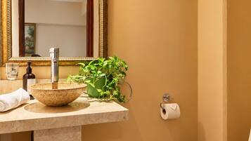 A bathroom with a marble sink, a large mirror, a toilet, and a trash bin.