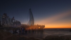 Eine Brücke mit einem markanten Design, die auf ein Gewässer im Zwielicht blickt.
